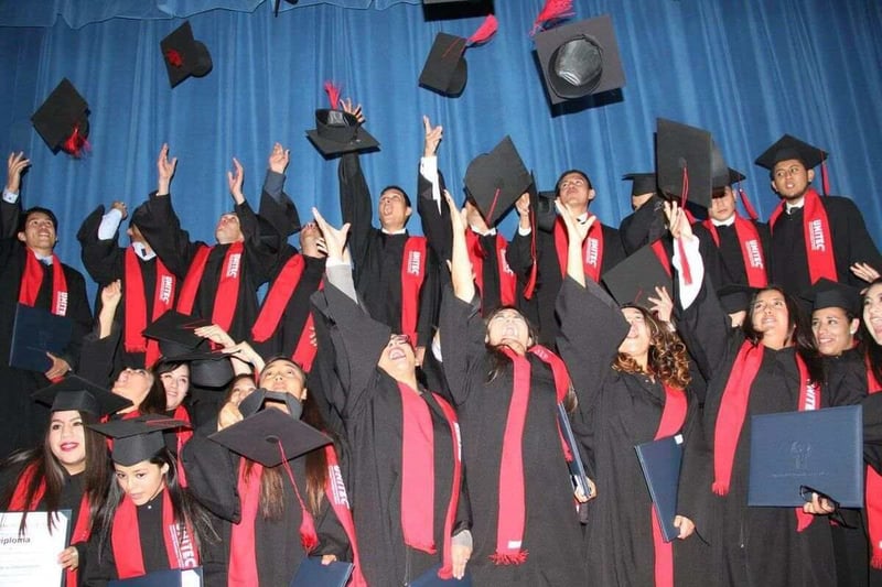 Estudiantes graduados lanzando birretes al aire durante ceremonia de graduación en UNITEC.
