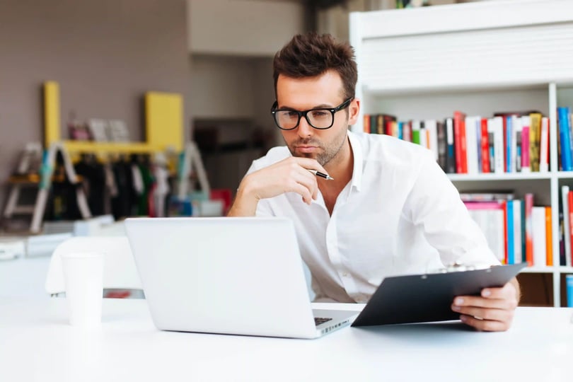 Hombre profesional revisando documentos frente a una computadora, representando opciones para estudiar una licenciatura ejecutiva mientras se trabaja)