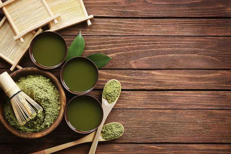 Té matcha en polvo con utensilios tradicionales japoneses sobre mesa de madera - Ingredientes naturales y preparación artesanal de matcha