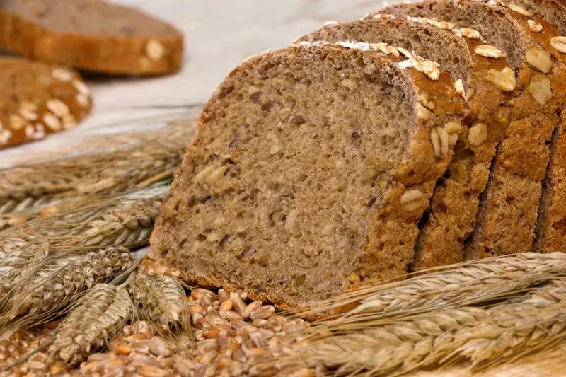 Pan integral con granos enteros y espigas de trigo, símbolo de alimentos saludables y ricos en fibra