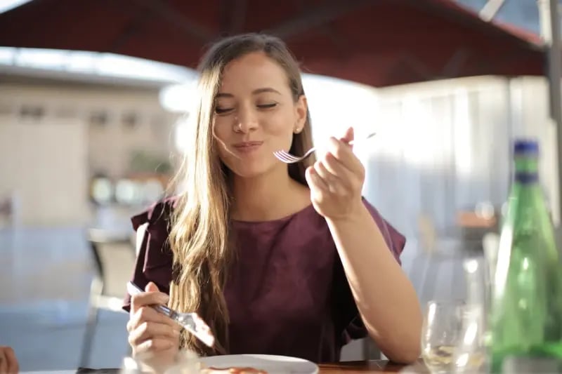 Joven comiendo en un restaurante al aire libre, disfrutando de una comida saludable y equilibrada