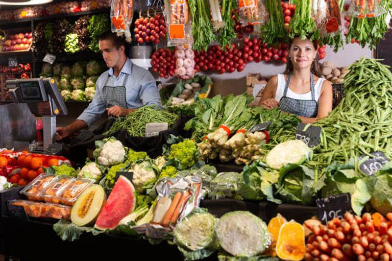 Puesto en mercado con frutas y verduras frescas como tomates, lechugas y zanahorias - Productos locales saludables