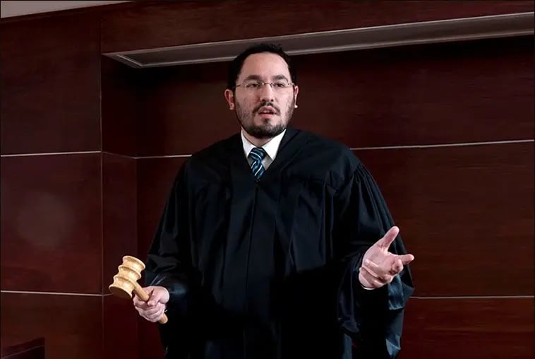 Juez en una sala de tribunal sosteniendo un mazo, representando la práctica de la justicia y el derecho.