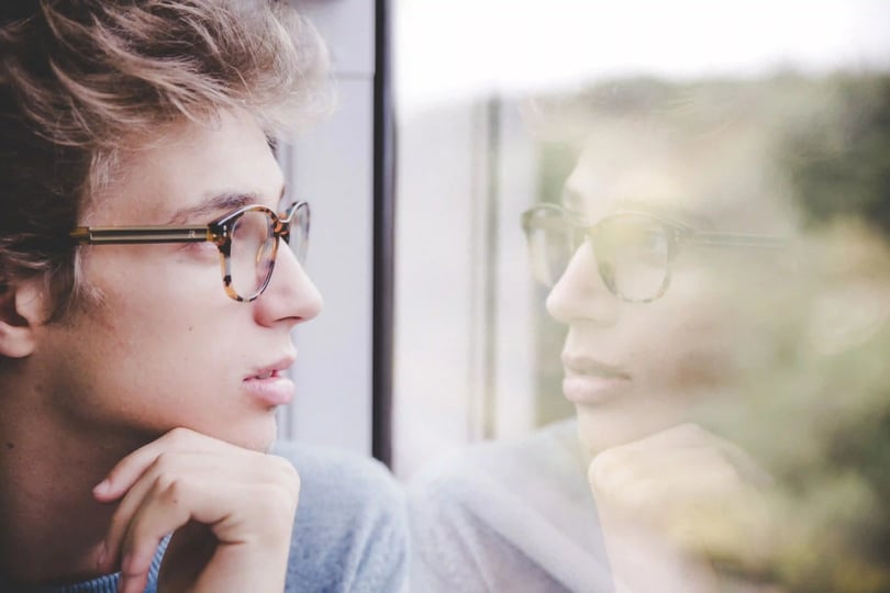Joven reflexionando frente a una ventana, ideal para elegir carrera.