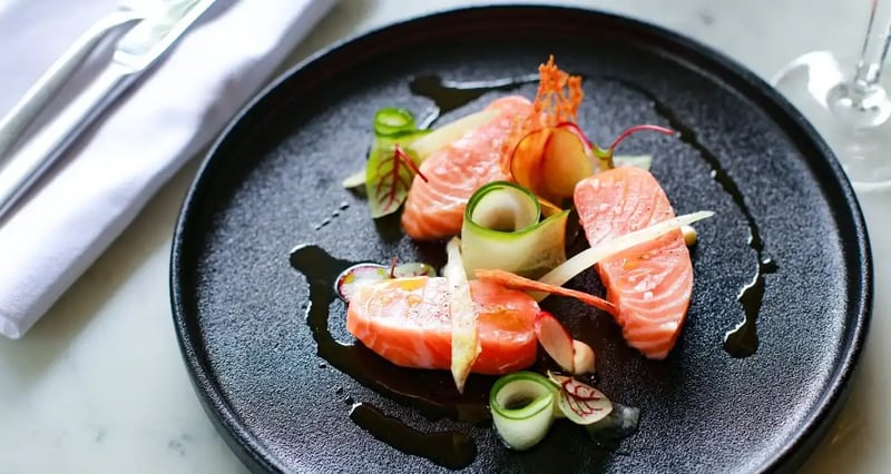 Presentación moderna de salmón con vegetales frescos en un plato negro - Alta cocina contemporánea