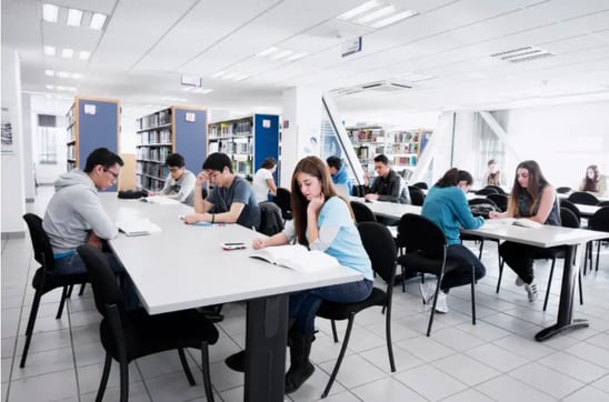 Estudiantes en la biblioteca de UNITEC estudiando y trabajando en equipo.