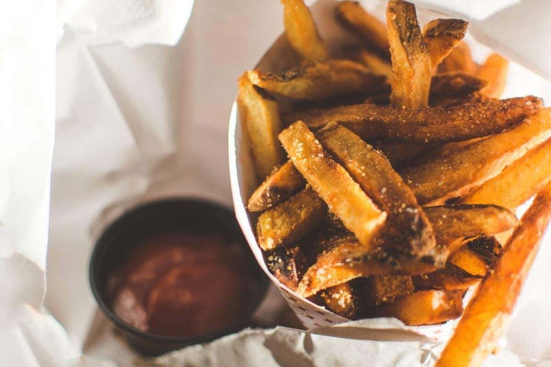 Papas fritas crujientes con salsa de tomate en un cono de papel.