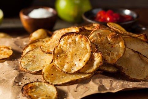 Rebanadas de papas horneadas sazonadas, servidas sobre papel encerado.