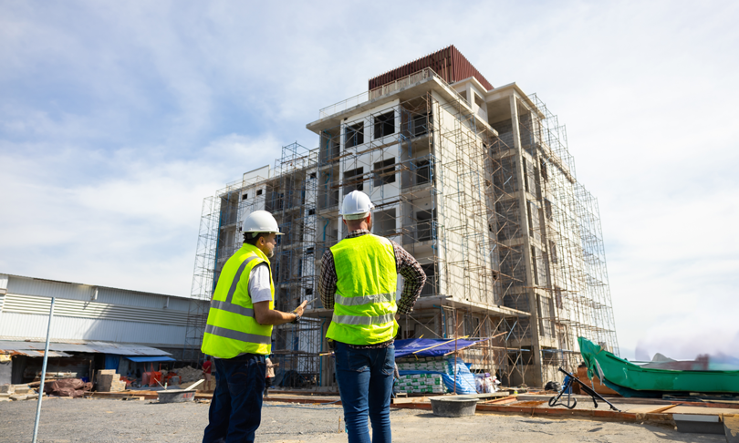 Líderes de proyectos de construcción supervisando obra en desarrollo con cascos de seguridad