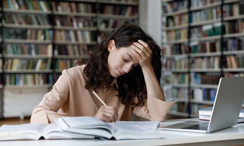 Estudiante universitario recibiendo asesoría académica en la biblioteca.