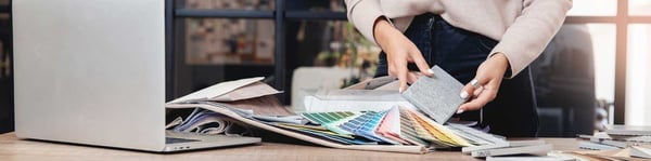 Manos seleccionando muestras de materiales y paletas de colores, representando el proceso creativo de un diseñador de interiores.