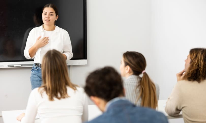 Docente impartiendo clase a estudiantes universitarios en un aula moderna, ejemplo del trabajo de un Licenciado en Educación.