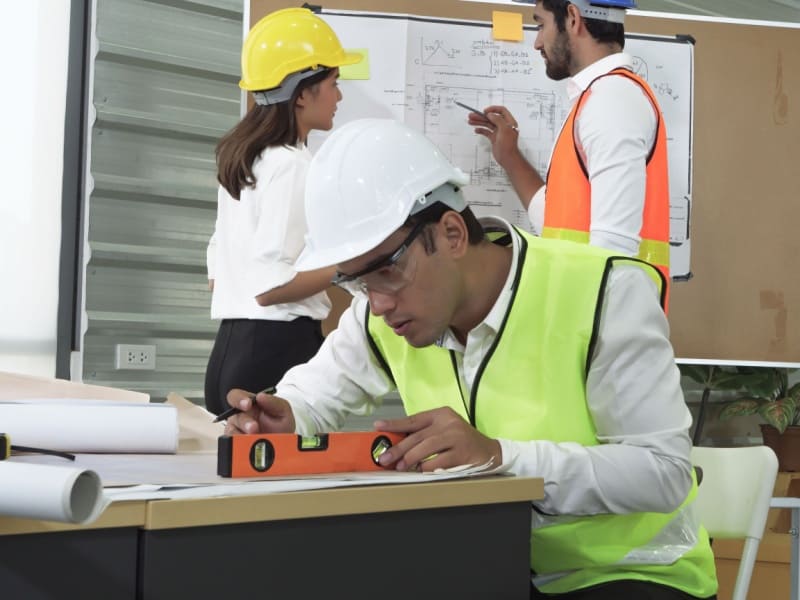 Equipo de ingeniería analizando planos y materiales sustentables para optimizar procesos y minimizar residuos industriales.