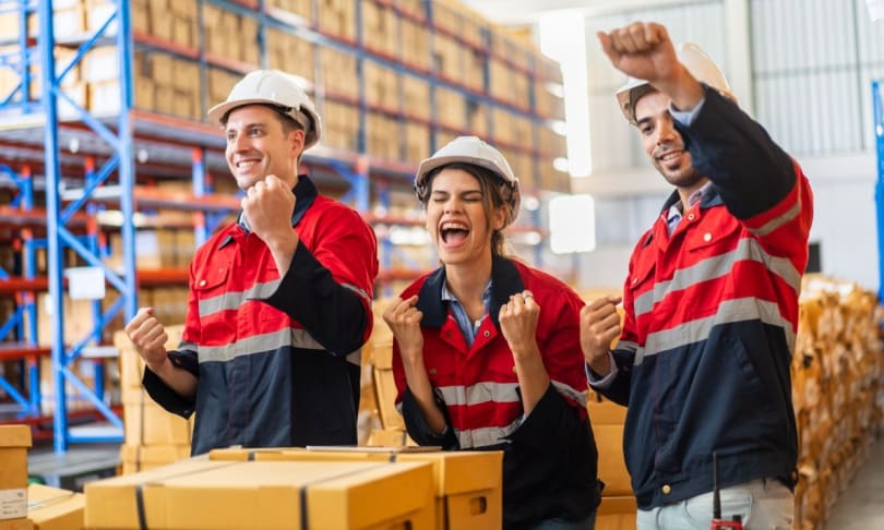 Equipo de ingenieros en logística celebrando resultados en un almacén y centro de distribución