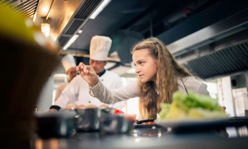 Estudiante de gastronomía trabajando en cocina escolar equipada durante formación universitaria
