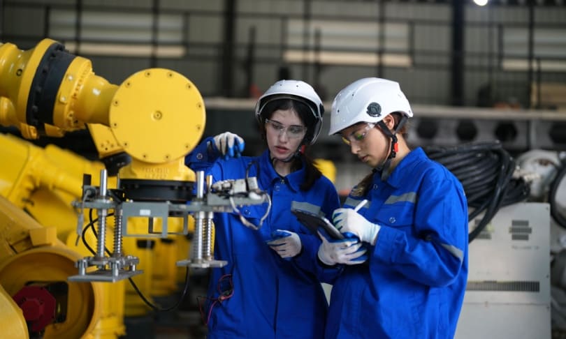 Estudiantes de ingeniería mecatrónica trabajando con robot industrial