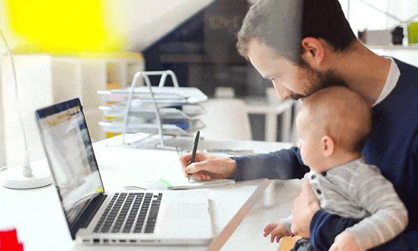 Padre estudiando en línea mientras cuida a su hijo pequeño