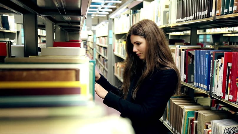 Estudiante en biblioteca universitaria, costo de universidad privada y rendimiento académico