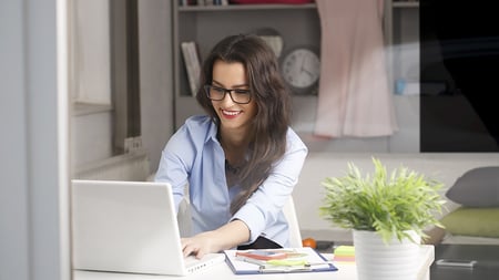 Estudiante feliz estudiando Administración de Empresas en modalidad en línea desde casa