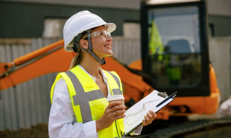 Ingeniera civil en obra con planos y casco de seguridad