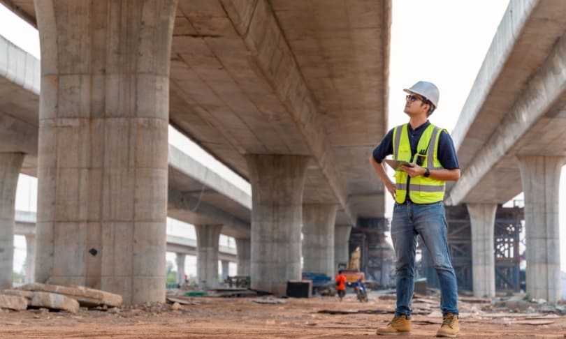Ingeniero civil supervisando construcción de puente en obra vial