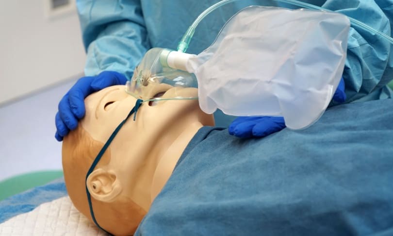 Simulador clínico de paciente siendo ventilado con bolsa de resucitación en un laboratorio de simulación médica.