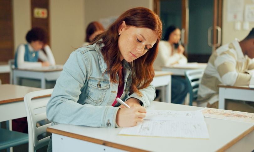 Egresada de preparatoria realizando examen en aula de universidad