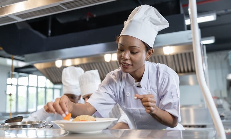 Estudiante de Gastronomía preparando y presentando un platillo durante una práctica en una cocina universitaria.