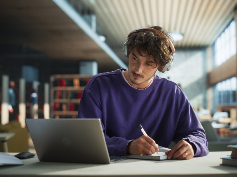 Estudiante universitario tomando clases en línea con laptop y audífonos