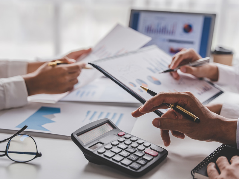 Equipo de contadores revisando informes financieros y estados contables con calculadora