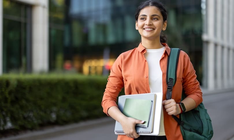 Profesionista con libros y computadora que se prepara para estudiar una maestría en Educación y ampliar sus oportunidades laborales.