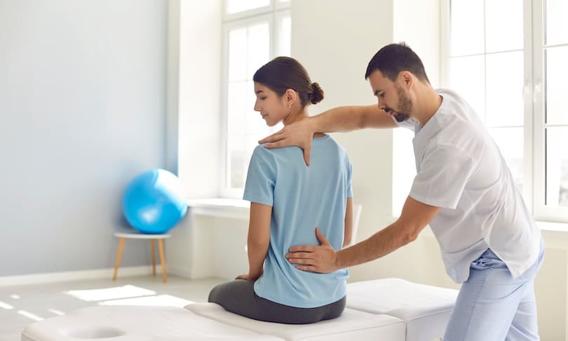 Fisioterapeuta revisando la condición de los músculos de la espalda baja de la paciente 